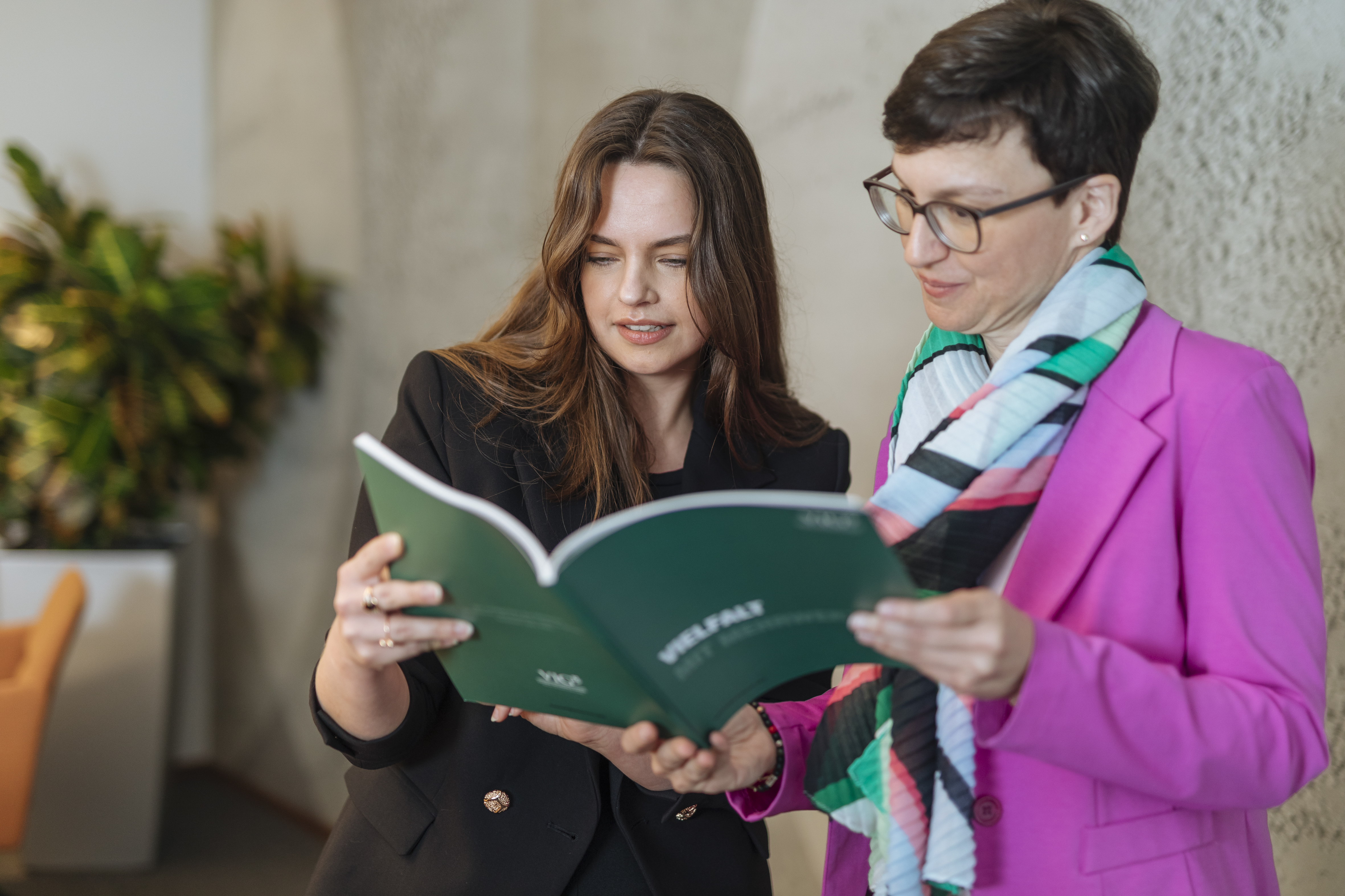 Two women leaf through a report